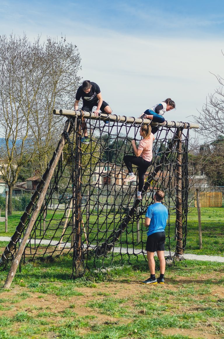 Persone che scalano una rete in un percorso a ostacoli all’aperto.