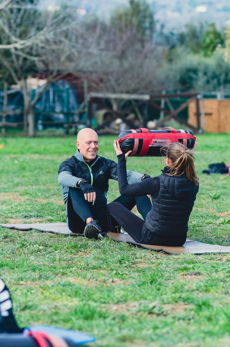 A couple sits on a yoga mat at the Ego Wellness Center, surrounded by nature