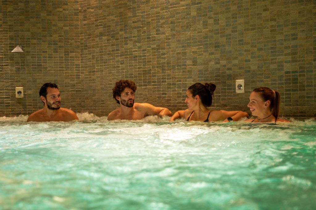 Quattro persone che si rilassano insieme in una vasca idromassaggio in spa