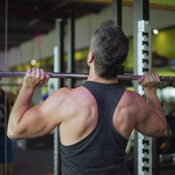 Uomo che solleva un bilanciere in palestra per esercizio di forza presso Ego Wellness.