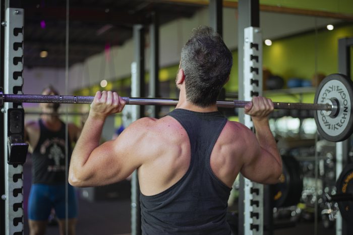Uomo che solleva un bilanciere in palestra per esercizio di forza presso Ego Wellness.