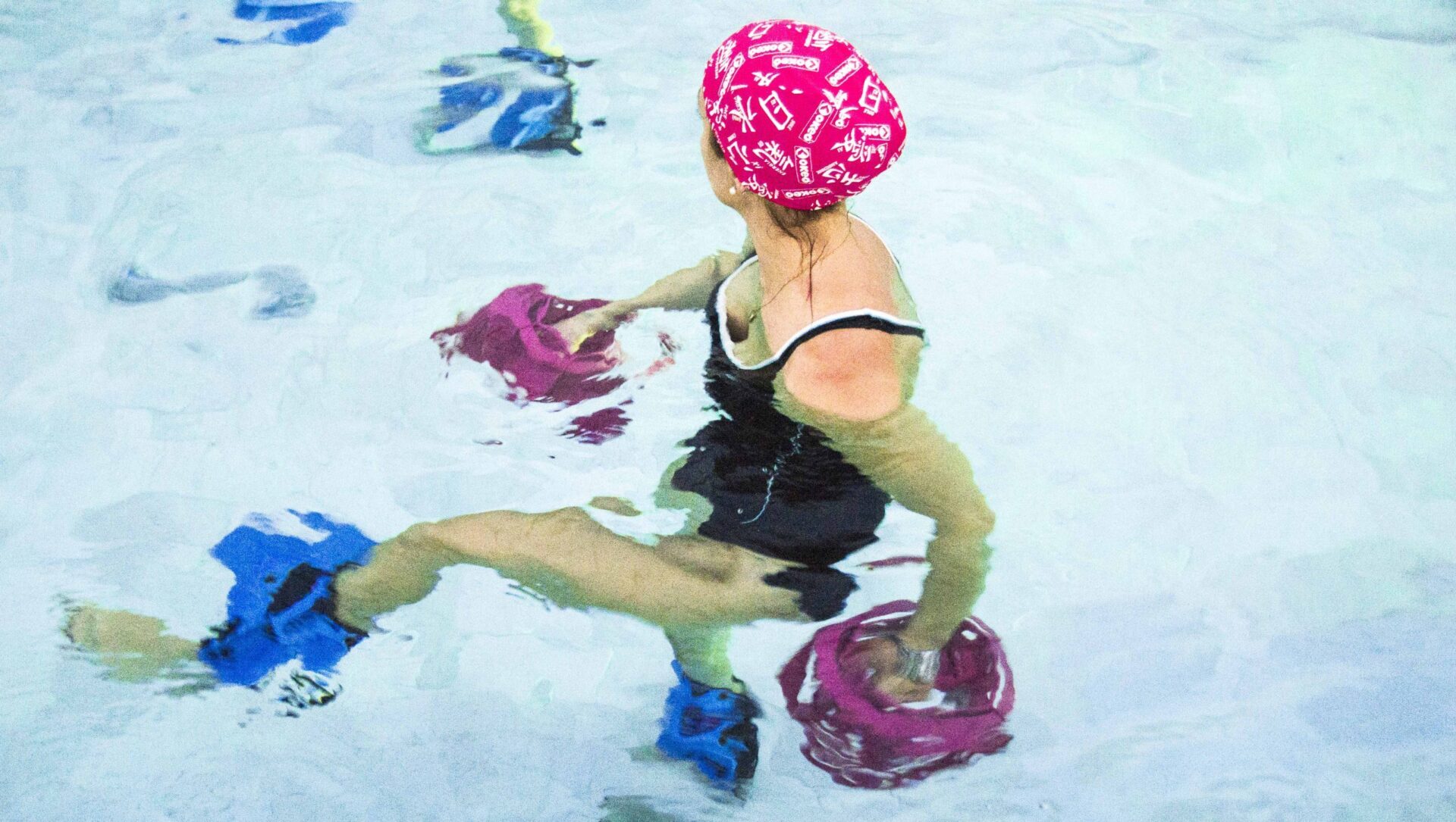 Donna in piscina durante esercizi con attrezzi acquatici per la forza.