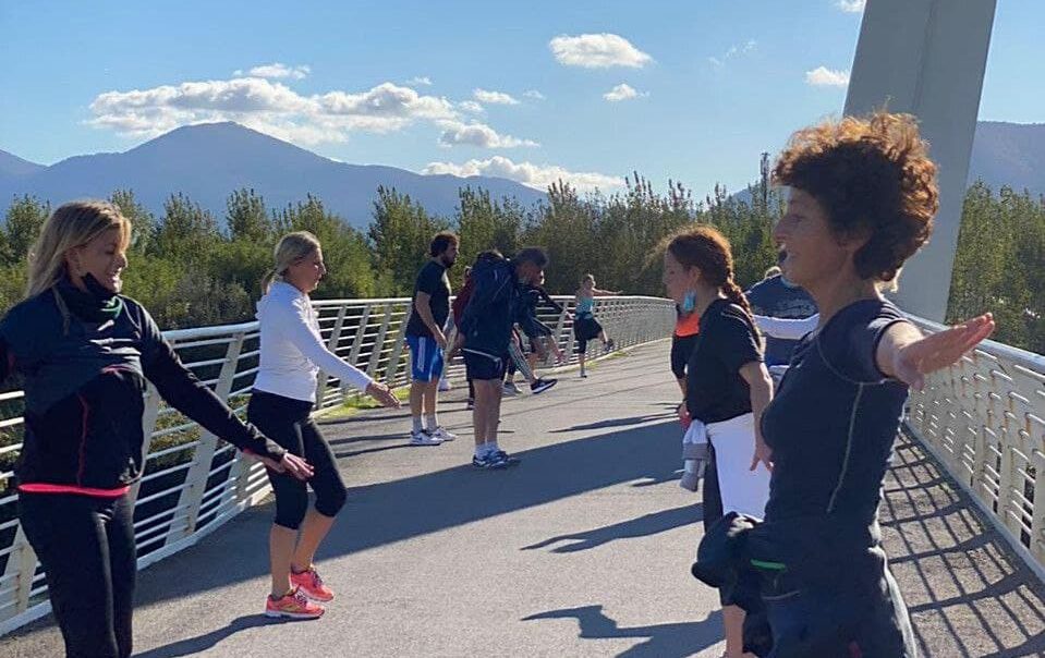 Sessione di allenamento all'aperto su un ponte con partecipanti in esercizi di stretching.