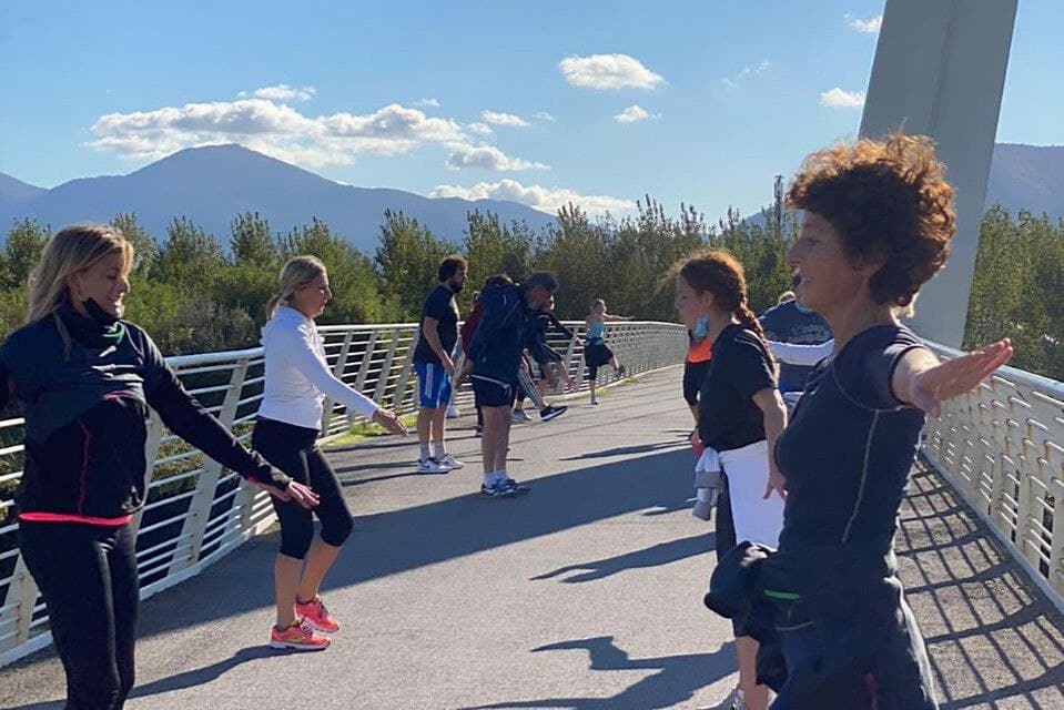 Sessione di allenamento all'aperto su un ponte con partecipanti in esercizi di stretching.
