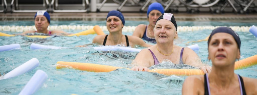Gruppo di donne durante una lezione di acquagym in piscina con tubi galleggianti