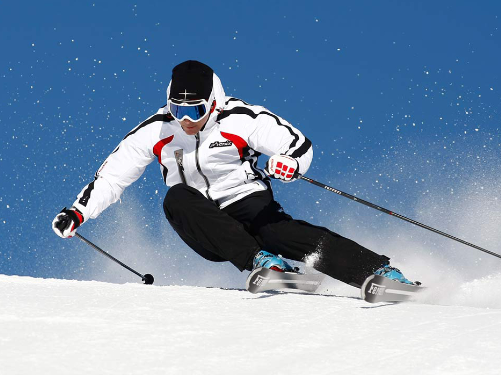Sciare in pista, atleta con giacca bianca e sci, neve e cielo azzurro.