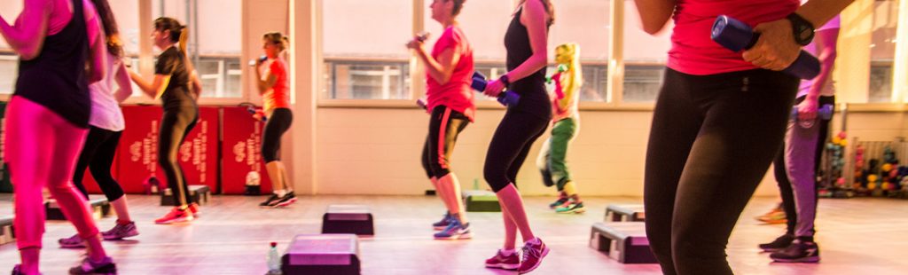 Lezione di fitness al chiuso con persone che usano pesi e step