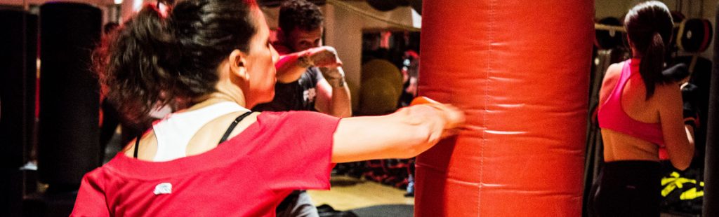 Lezione di fit boxe con partecipanti che si allenano su sacchi da boxe