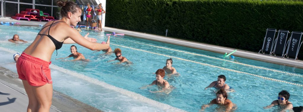 Istruttrice guida una lezione di idrobike in piscina con partecipanti