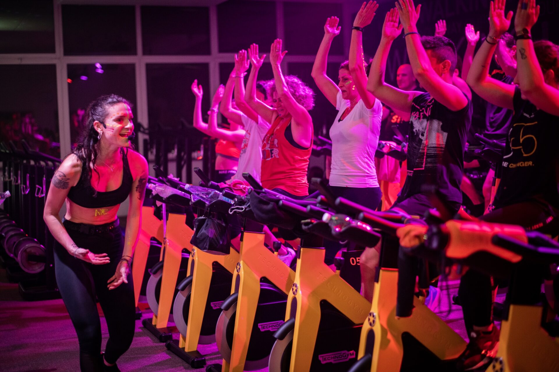 Istruttrice motivante guida una classe di indoor cycling con partecipanti entusiasti.