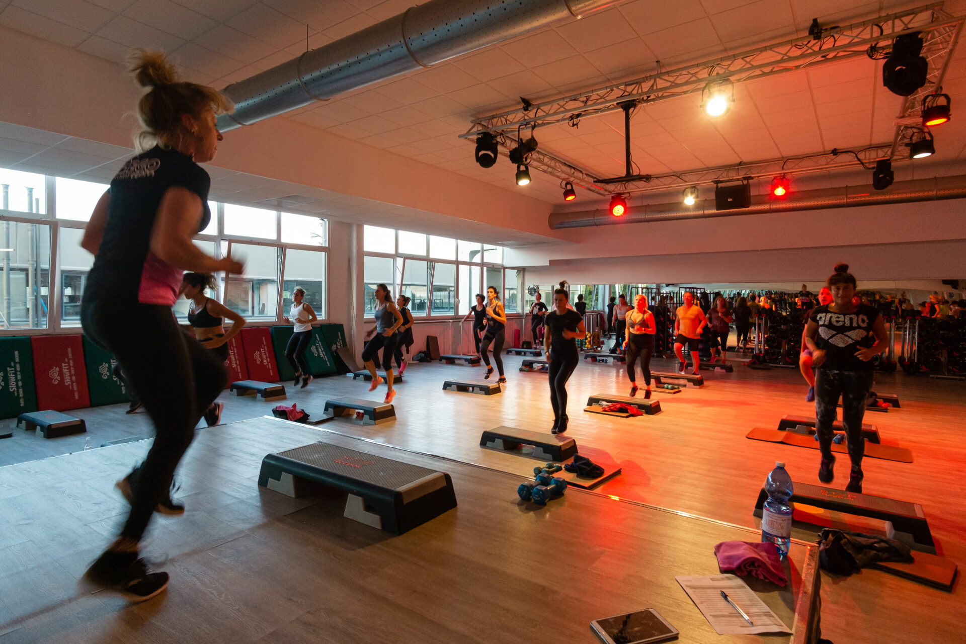 Classe di allenamento di gruppo con esercizi di step aerobico in una palestra moderna.