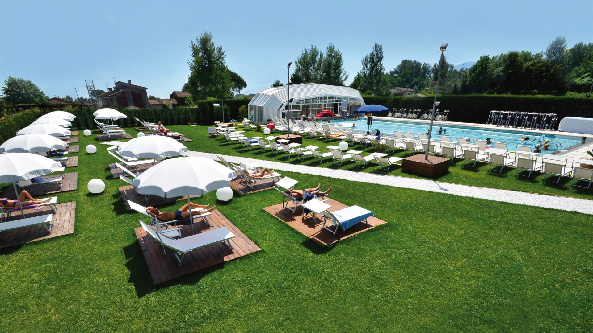 Piscina all'aperto con solarium, lettini e ombrelloni bianchi in ambiente esclusivo